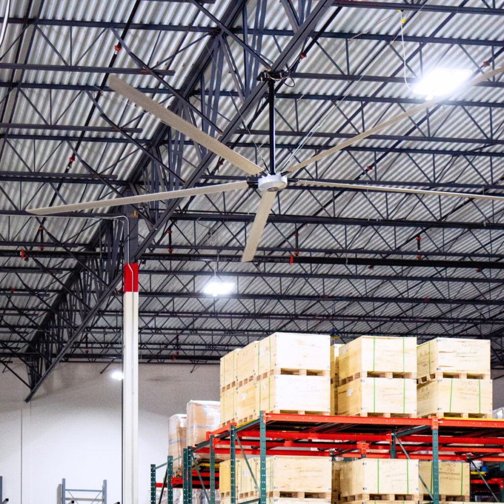 Déstratificateur HVLS aluminium au-dessus des racks et cartons d'un entrepôt logistique