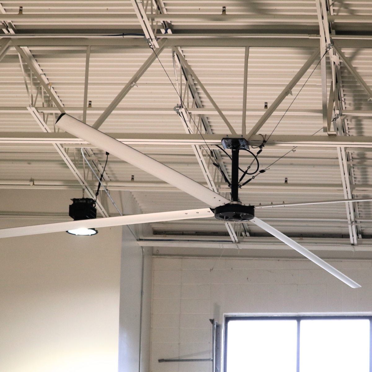 Ventilateur HVLS Hunter ECO sous charpente dans un atelier grand volume