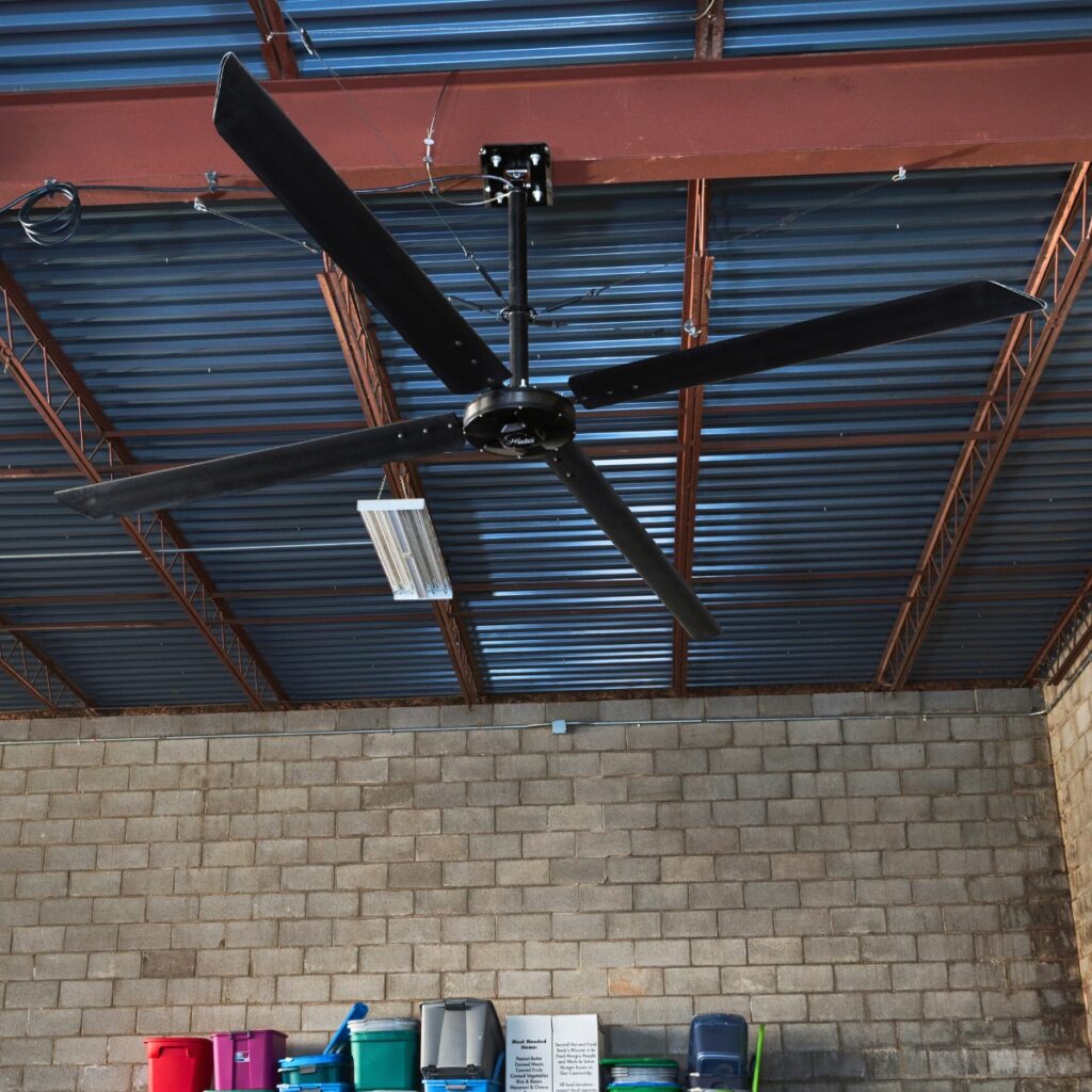 Déstratificateur Hunter ECO noir sous le plafond bleu d'un atelier aux poutres rouges