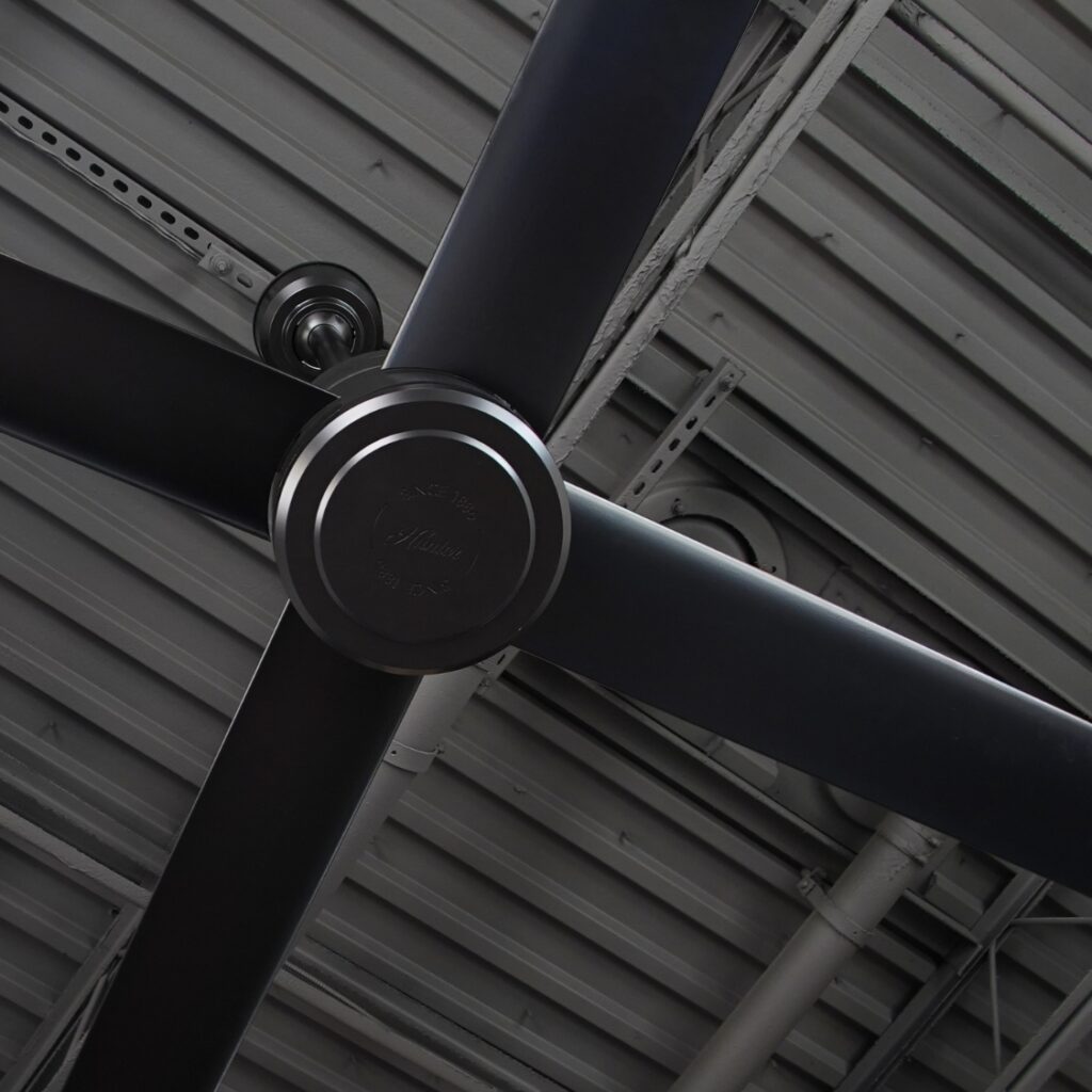 Ventilateur Hunter TRAK Edge noir vu de près sous une charpente métallique sombre