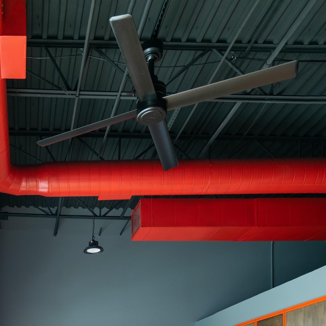 Ventilateur Hunter TRAK Edge noir vu de biais sous un plafond technique bleu-vert