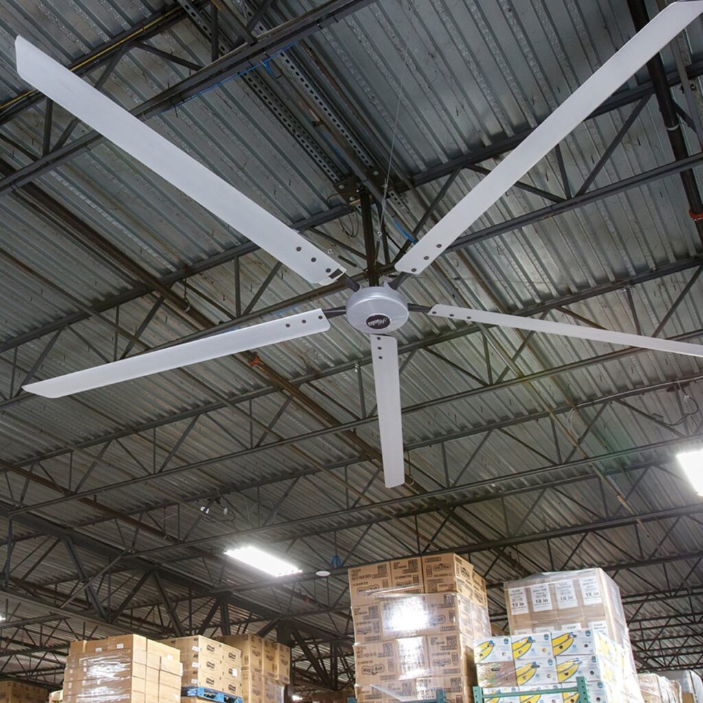 Ventilateur HVLS aluminium à six pales sous la charpente d'un entrepôt de stockage