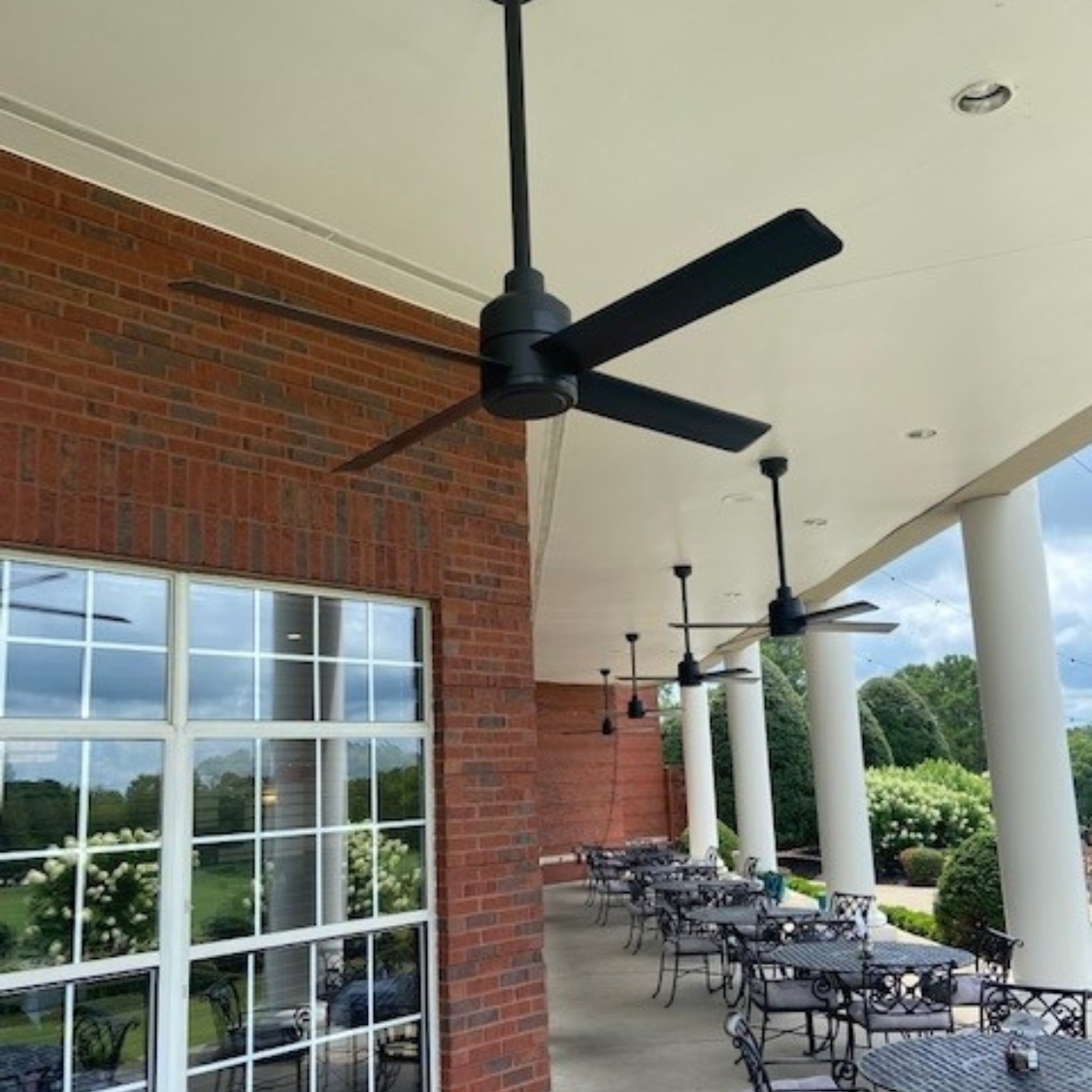 Ventilateur Hunter TRAK Edge sous une terrasse couverte à colonnes et mur de brique